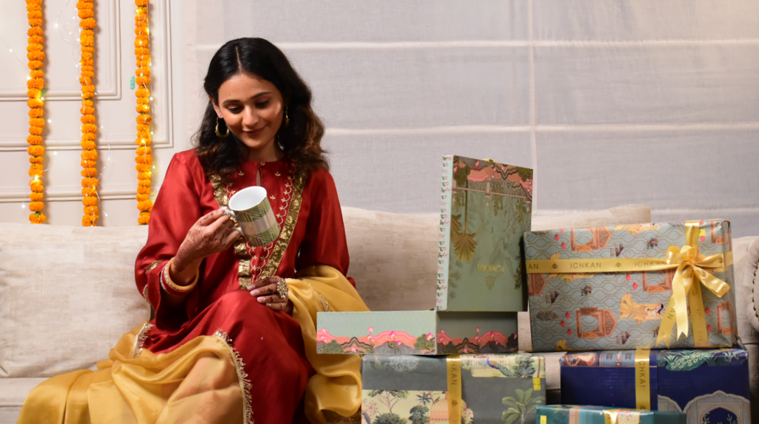 A women looking at the Mug sitting on a sofa along with many gift packages from the brand ICHKAN
